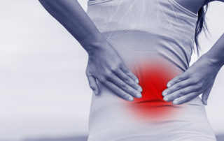 Back pain - woman having painful muscle injury in lower back. Fitness girl sport girl with sports injury outdoor. Blue filter with red zone circle showing the painful area.
