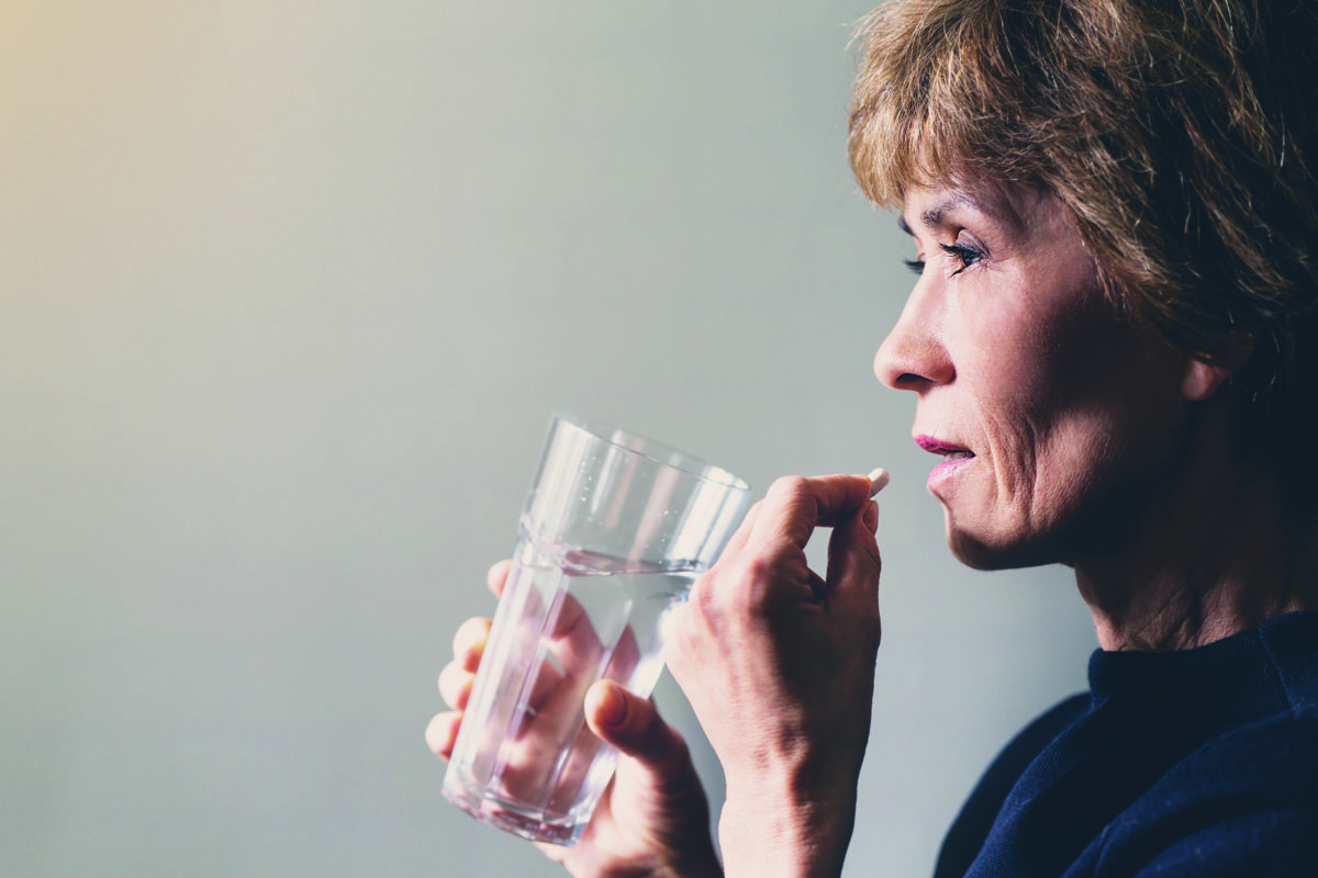 Adult woman with a pill and a glass of water / healthcare concept