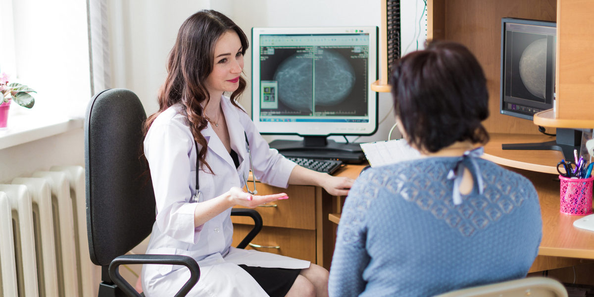The young happy breast specialist talking with the patient in her office